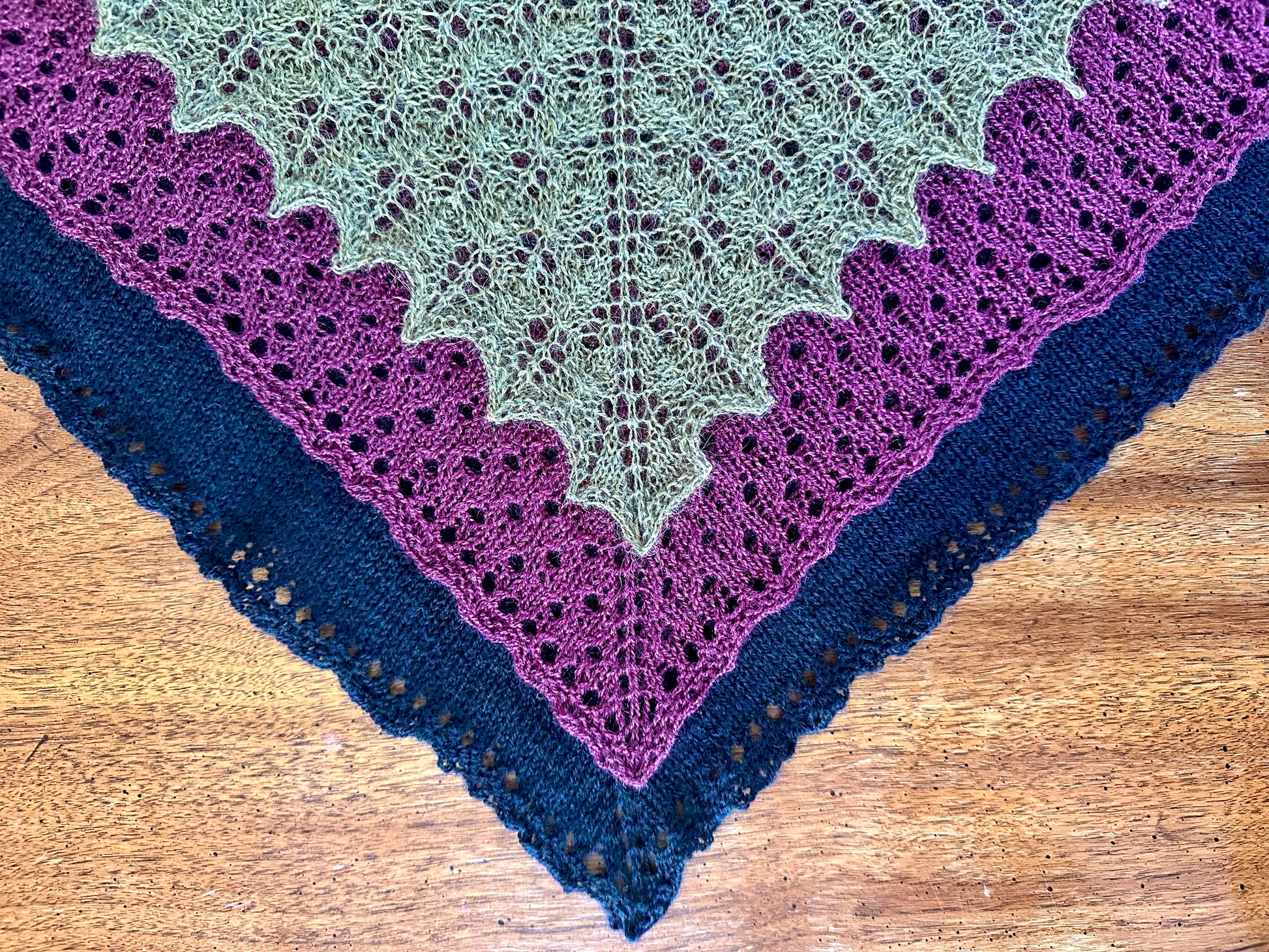Three knitted shawls on a wooden surface