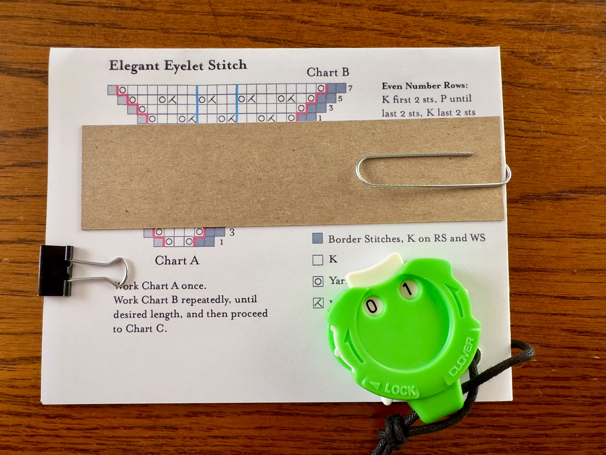 Knitting chart with green row counter attached

